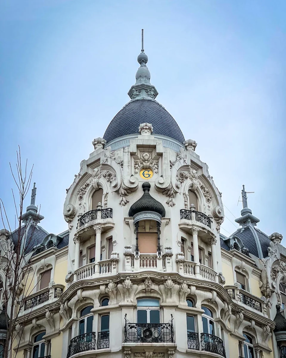 historical building with a grand facade and three domes, one in the front and then one of either side.